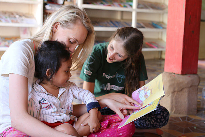 Projects Abroad Care & Community volunteers read a story with child at a day care center in Cambodia