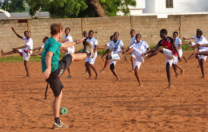 A Projects Abroad volunteer leads warm-up exercises at the Soccer Project in Togo